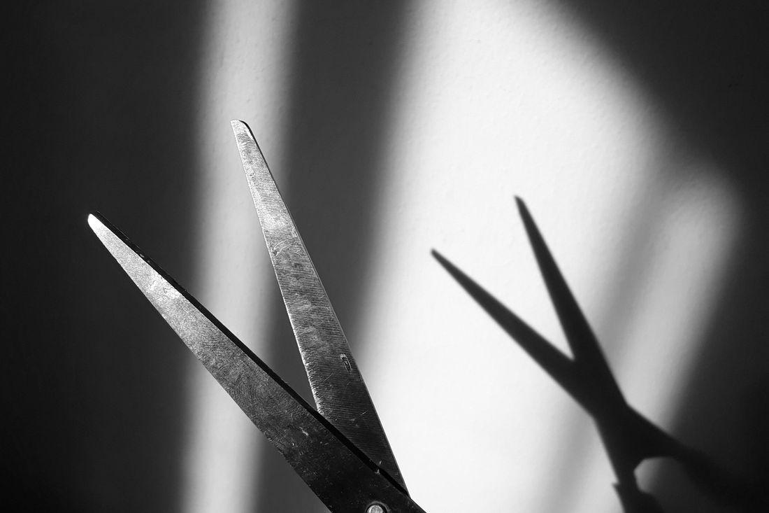 Two pairs of barber scissors silhouetted against bright light