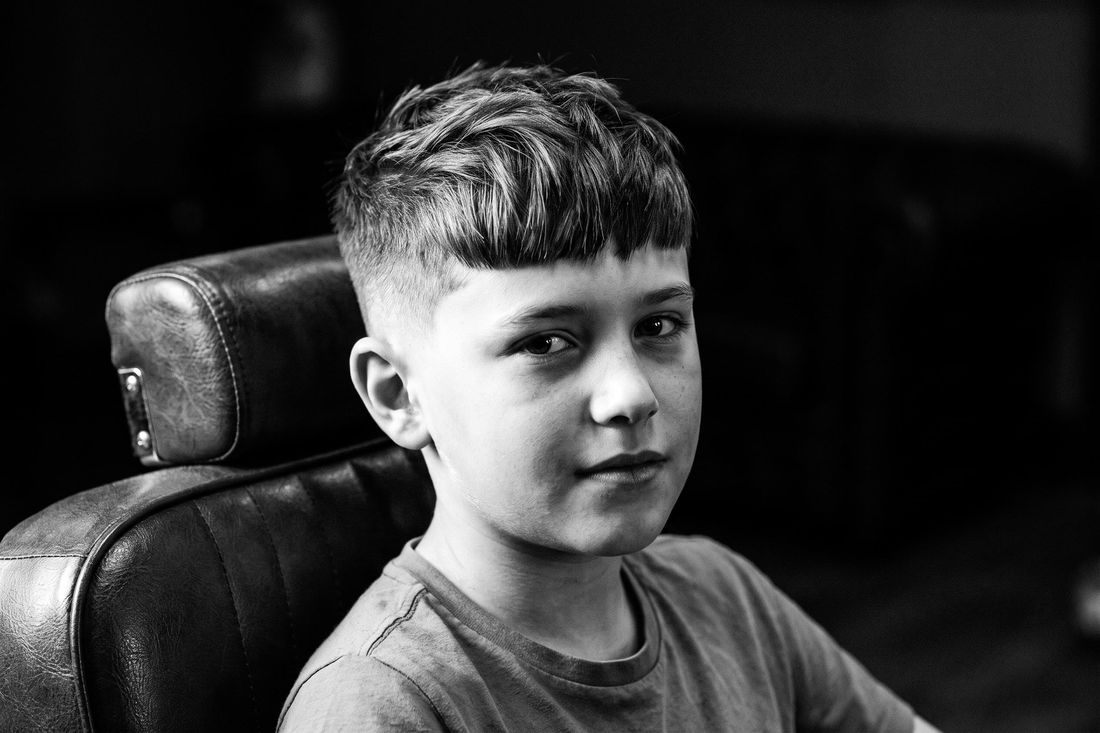 A boy with a textured crop, short sides and choppy bangs pushed forward