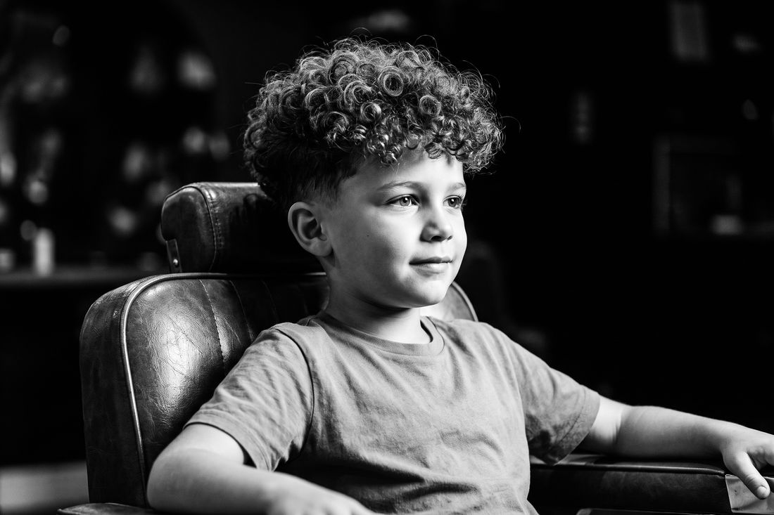 A boy with a curly top haircut, sides taken down and curls shaped long on top