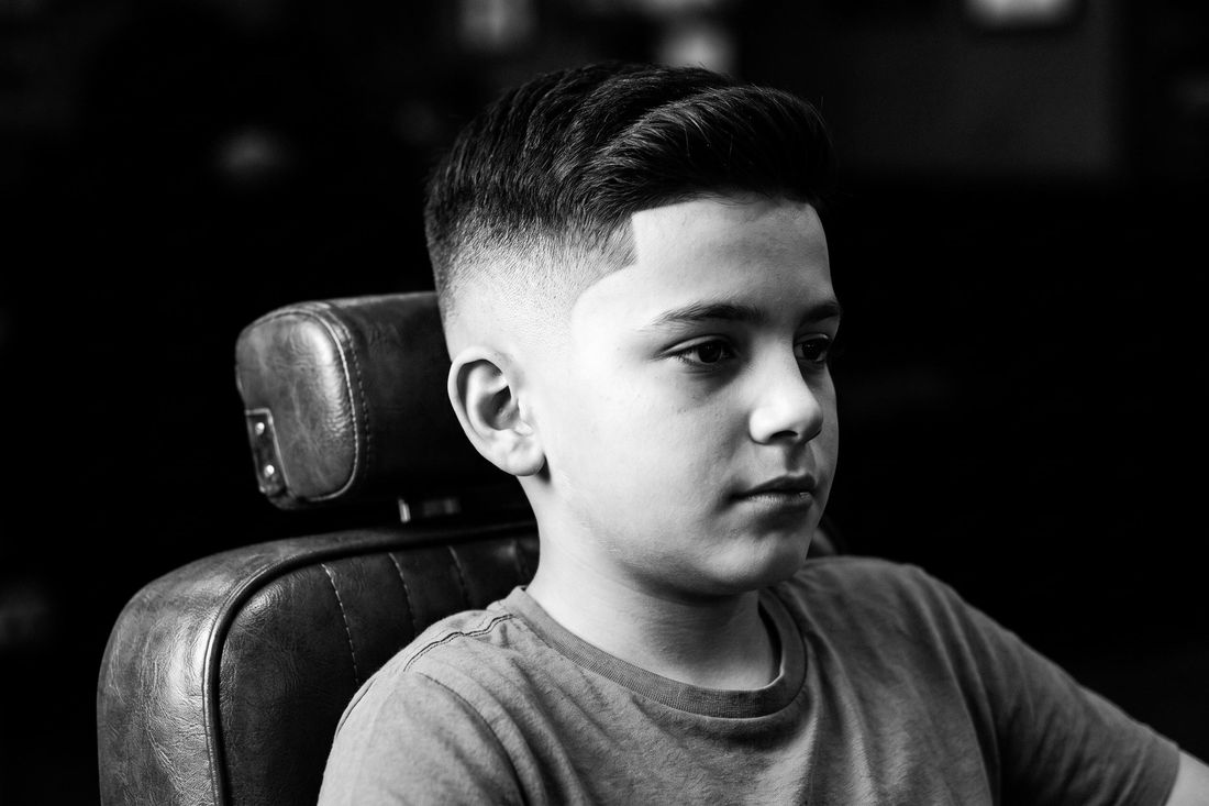 A boy with a skin fade, sides blended from bare skin into length on top