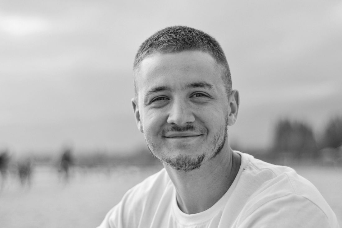 A smiling man with short hair outdoors
