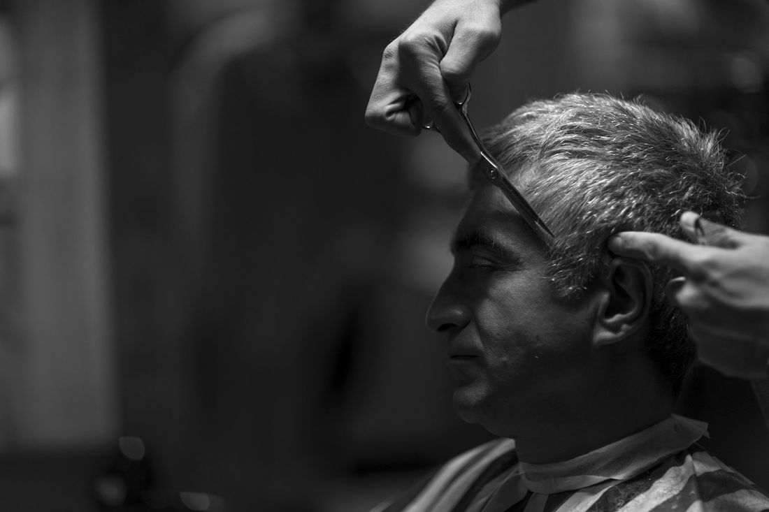 A barber combing a client's gray hair into place
