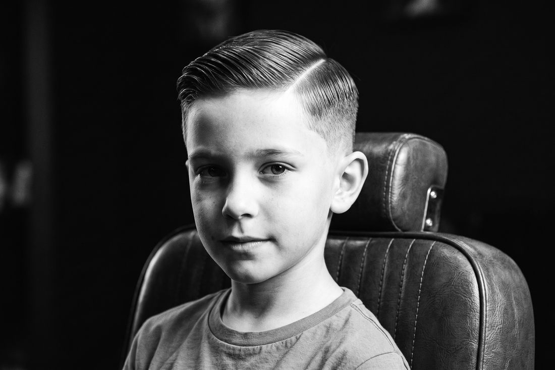 A boy with a tapered side part haircut, length swept cleanly over