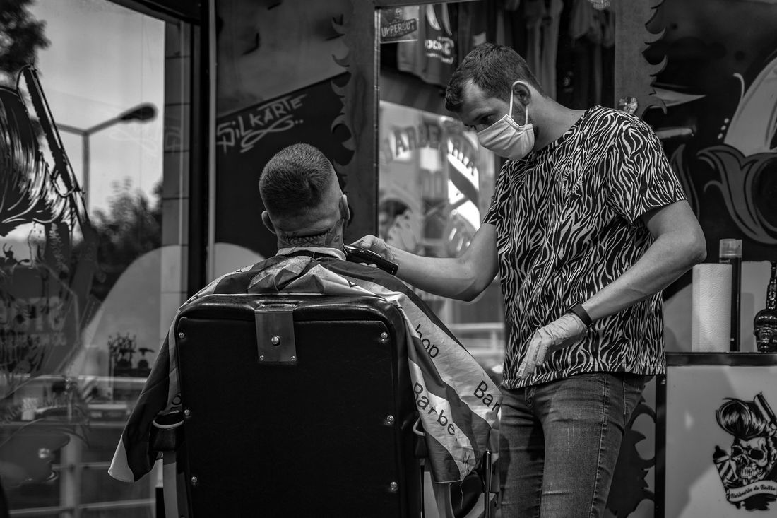 A barber cutting a client's hair in a shop with a colorful wall